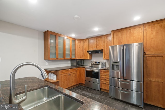 kitchen with under cabinet range hood, recessed lighting, appliances with stainless steel finishes, brown cabinetry, and a sink