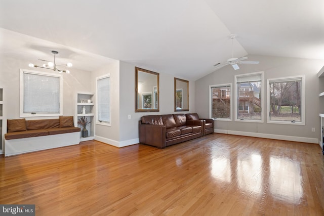 unfurnished living room with baseboards, built in features, light wood-type flooring, vaulted ceiling, and ceiling fan with notable chandelier