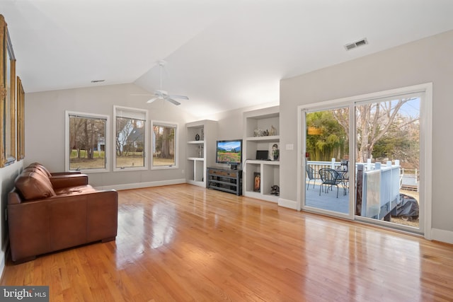 unfurnished living room with built in shelves, a ceiling fan, visible vents, and a wealth of natural light