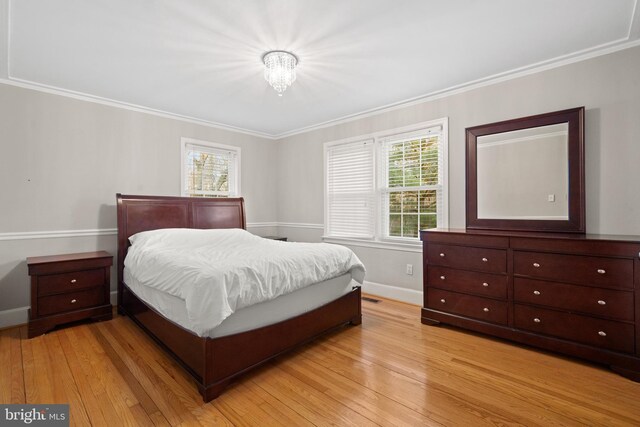 bedroom with light wood-type flooring, baseboards, and ornamental molding