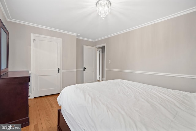 bedroom with ornamental molding, an inviting chandelier, and wood finished floors