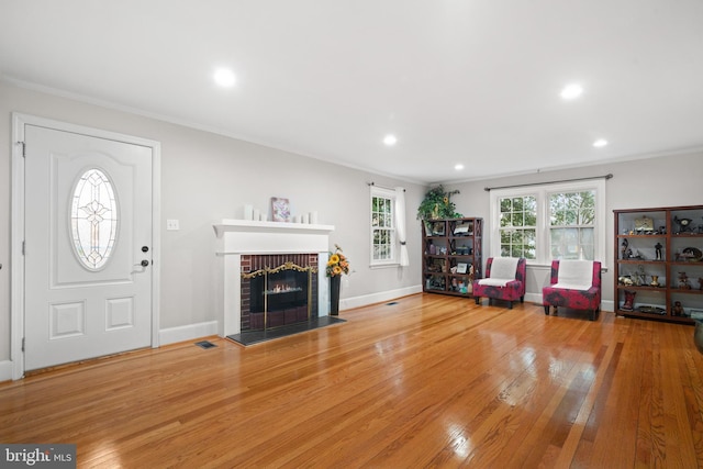 entrance foyer featuring a fireplace, crown molding, and wood-type flooring