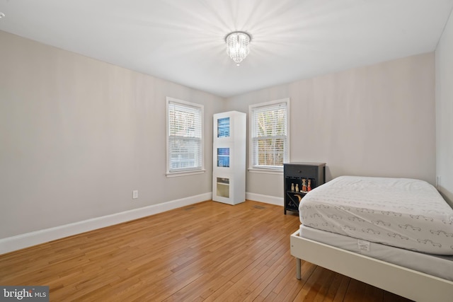 bedroom with an inviting chandelier, baseboards, and light wood finished floors