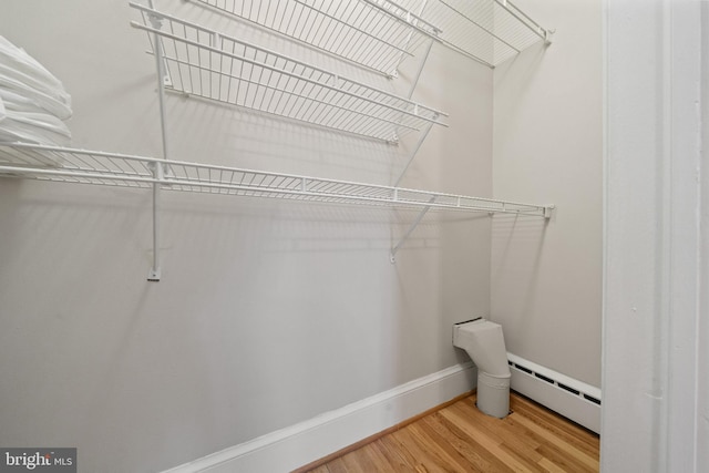 walk in closet with baseboard heating and wood finished floors