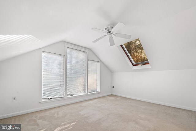 additional living space featuring lofted ceiling with skylight, baseboards, carpet floors, and ceiling fan