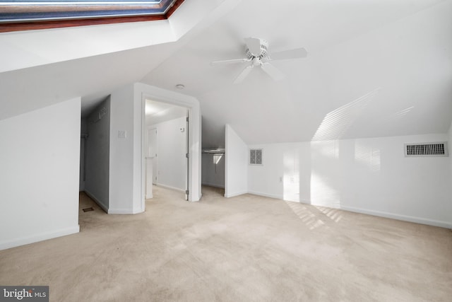 bonus room with vaulted ceiling with skylight, visible vents, carpet flooring, and ceiling fan