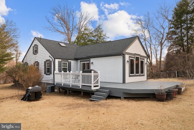 view of front facade featuring central AC, a shingled roof, a deck, and fence