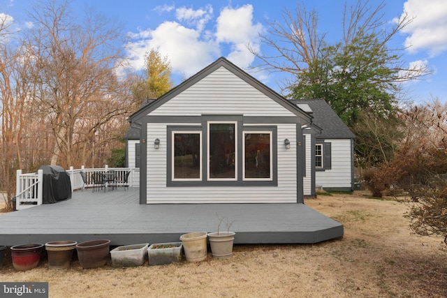 back of house featuring a lawn and a wooden deck