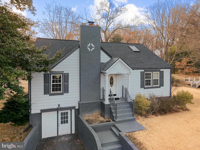 view of front of home with a chimney and roof with shingles