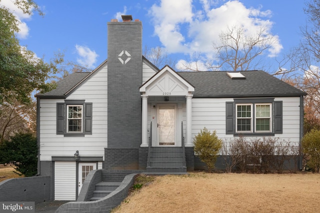 view of front of house featuring an attached garage, a chimney, and a shingled roof