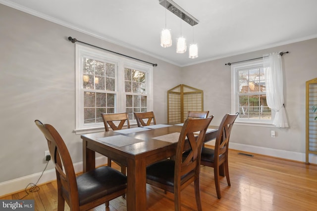 dining area featuring baseboards, visible vents, crown molding, light wood-type flooring, and a chandelier