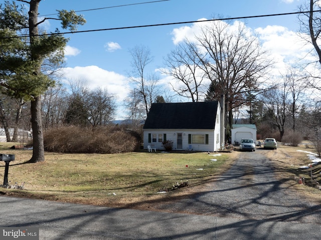 view of front of property with a front lawn, an outdoor structure, and dirt driveway