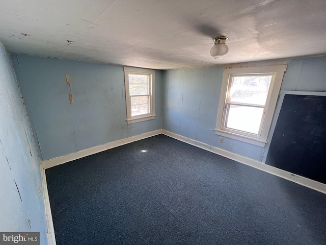 unfurnished room featuring dark colored carpet and baseboards