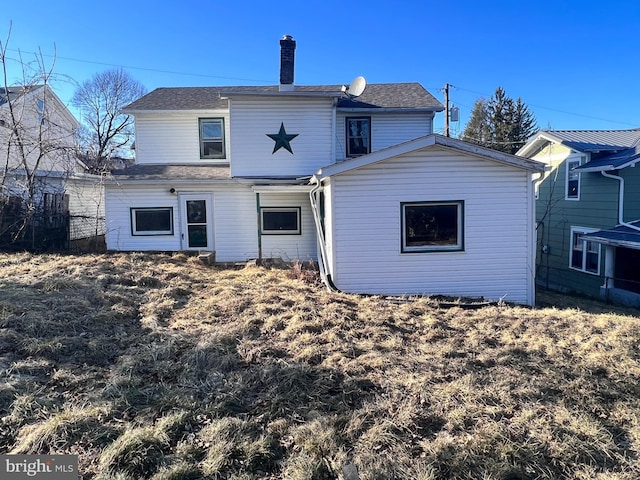 rear view of house with a chimney and fence