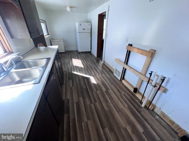 kitchen featuring a sink, freestanding refrigerator, light countertops, baseboards, and dark wood-style flooring