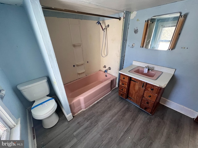 bathroom featuring toilet, wood finished floors,  shower combination, baseboards, and vanity