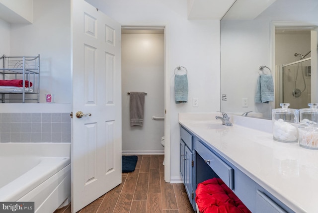 full bathroom with a shower stall, baseboards, wood tiled floor, toilet, and vanity