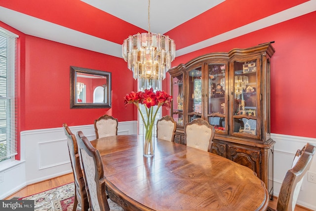 dining room with a chandelier, wainscoting, and wood finished floors