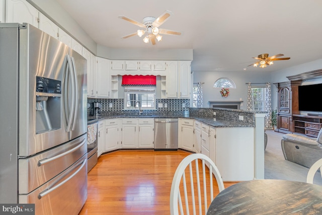 kitchen featuring tasteful backsplash, a sink, a peninsula, stainless steel appliances, and open shelves