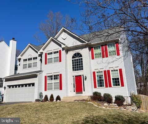 traditional home featuring a garage, a front lawn, and driveway