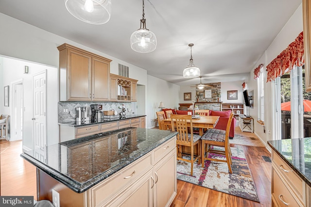 kitchen featuring tasteful backsplash, ceiling fan, open floor plan, light wood-style flooring, and hanging light fixtures