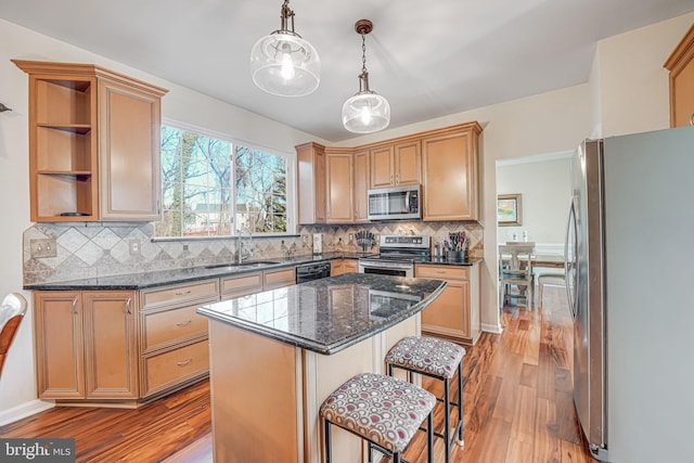 kitchen with a sink, stainless steel appliances, backsplash, and wood finished floors