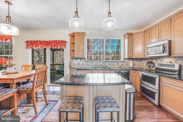 kitchen featuring a kitchen bar, a sink, a kitchen island, tasteful backsplash, and appliances with stainless steel finishes