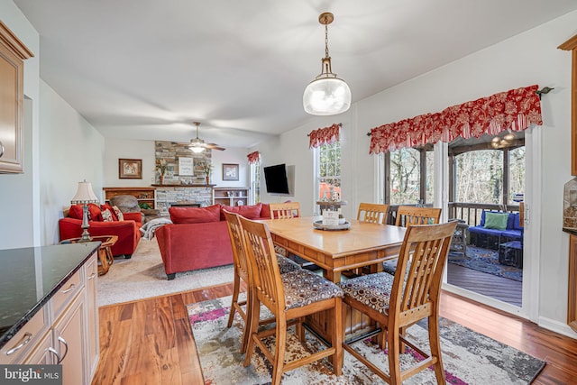 dining area with ceiling fan, hardwood / wood-style floors, and a fireplace