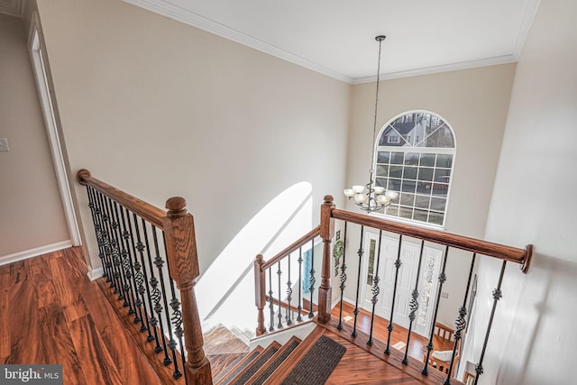 stairs featuring ornamental molding, baseboards, an inviting chandelier, and wood finished floors