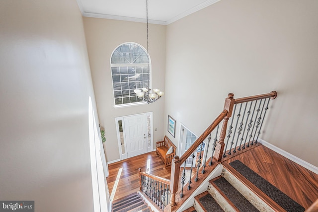 entryway featuring baseboards, a notable chandelier, wood finished floors, and crown molding