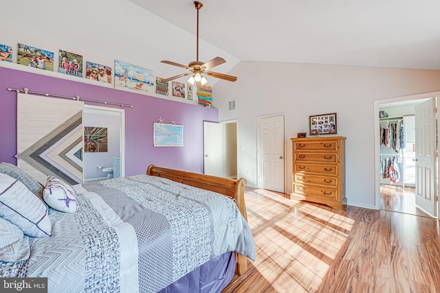 bedroom with visible vents, a walk in closet, high vaulted ceiling, wood finished floors, and ceiling fan