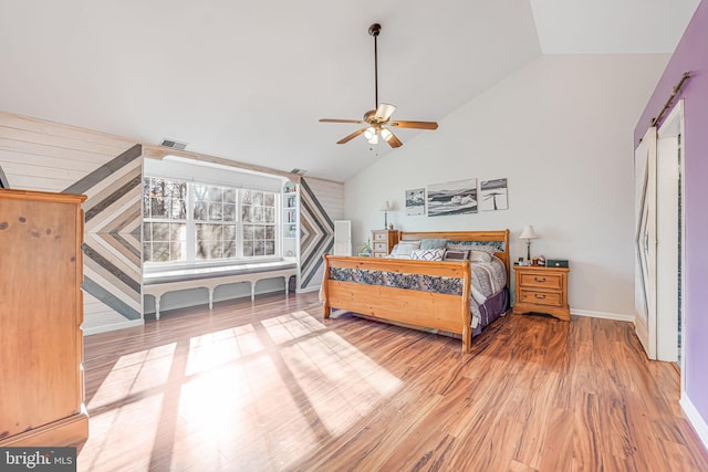 bedroom with a ceiling fan, wood finished floors, visible vents, baseboards, and lofted ceiling