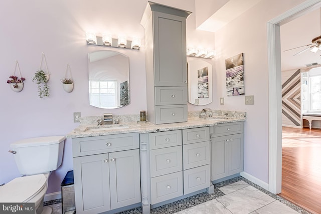 full bath featuring double vanity, toilet, a ceiling fan, and a sink