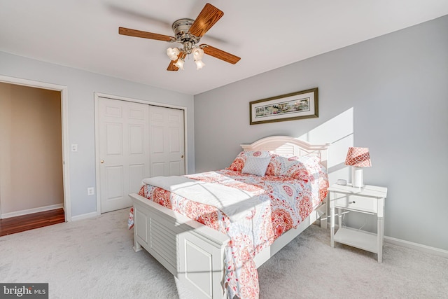 bedroom featuring a closet, light carpet, baseboards, and ceiling fan