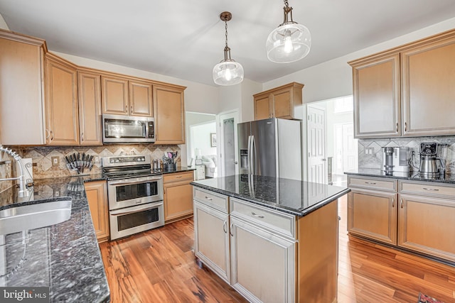 kitchen featuring light wood finished floors, a center island, stainless steel appliances, and a sink