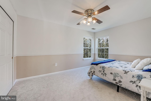 carpeted bedroom featuring baseboards, visible vents, a closet, and ceiling fan