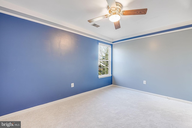 carpeted spare room featuring visible vents, baseboards, and ceiling fan