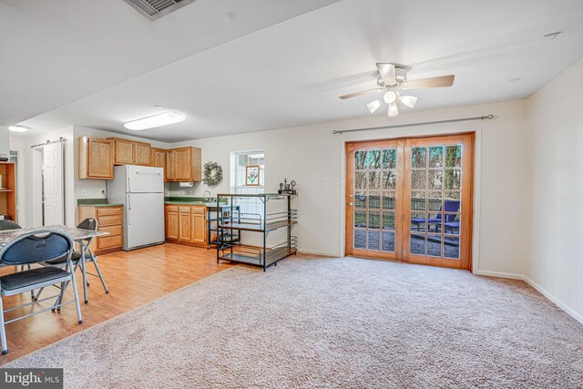 kitchen with visible vents, baseboards, freestanding refrigerator, a sink, and light carpet