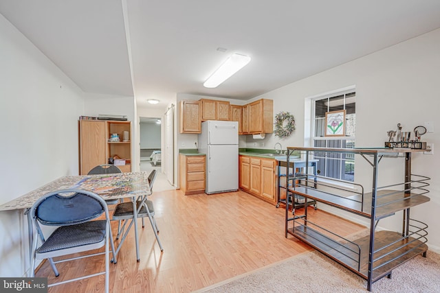 kitchen with a sink, light wood-type flooring, light brown cabinets, and freestanding refrigerator