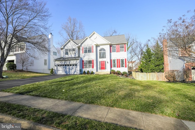 view of front of house featuring aphalt driveway, a front yard, a garage, and fence