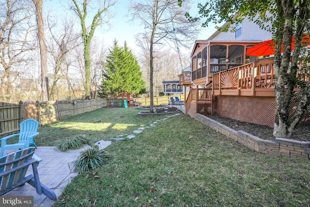 view of yard featuring a fenced backyard, a playground, a sunroom, a wooden deck, and a patio area