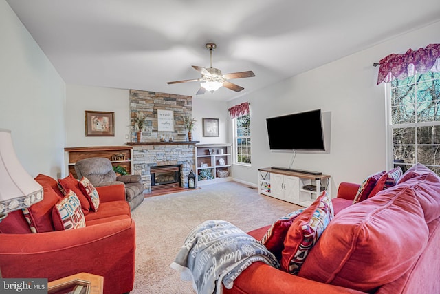 living room with a stone fireplace, carpet flooring, and ceiling fan