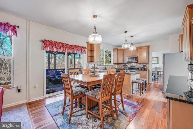 dining space featuring light wood finished floors, visible vents, and baseboards