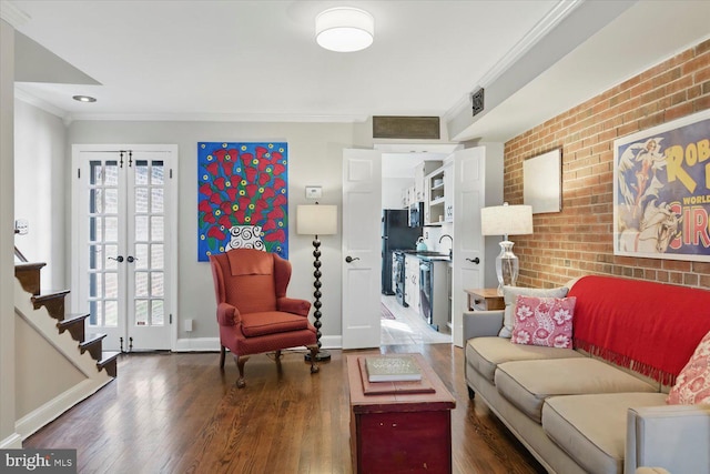 living area featuring crown molding, plenty of natural light, wood finished floors, and brick wall