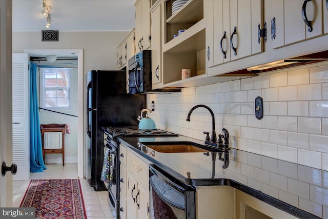 kitchen with dark countertops, visible vents, decorative backsplash, black appliances, and a sink