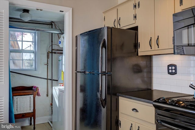 kitchen featuring black appliances, dark countertops, water heater, decorative backsplash, and washer / dryer