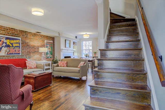 stairway featuring a fireplace, wood finished floors, and brick wall