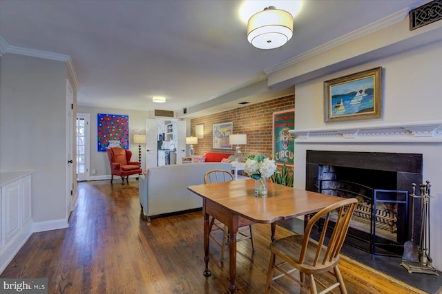 dining area with wood finished floors, baseboards, visible vents, a fireplace, and ornamental molding