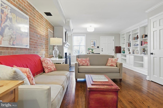 living room with visible vents, brick wall, built in shelves, crown molding, and wood finished floors