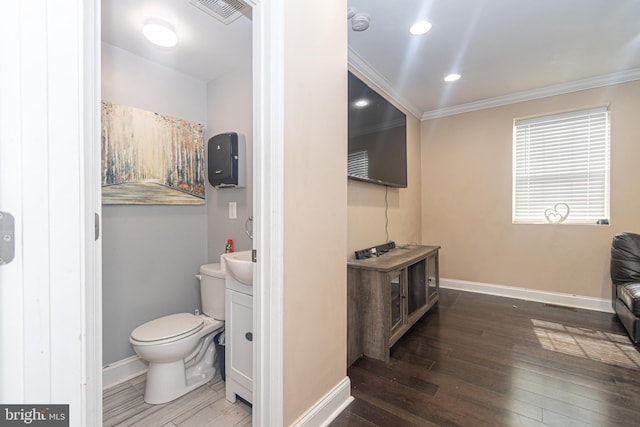 bathroom with vanity, wood finished floors, visible vents, baseboards, and crown molding